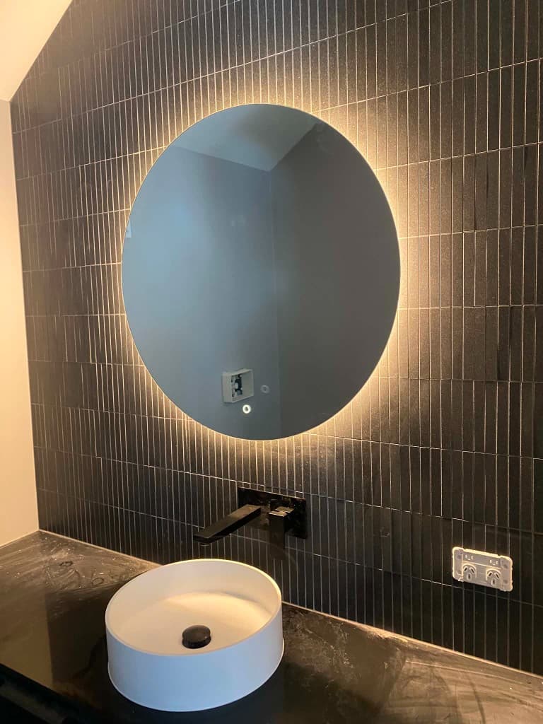 Backlit mirror and wall-mounted fittings in a modern bathroom